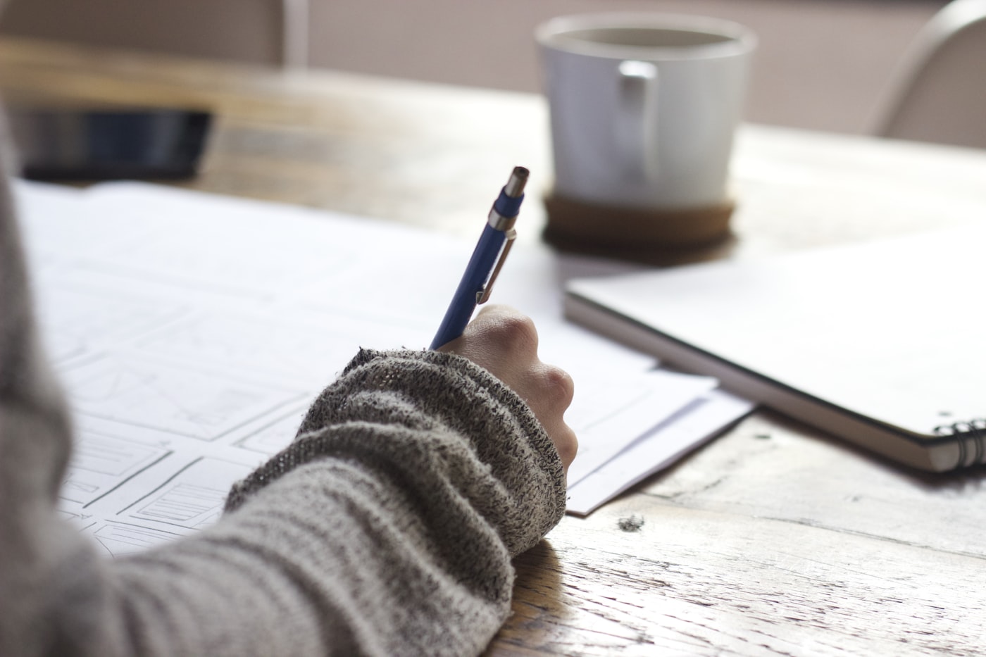 Copywriter drafting website and campaign copy by hand and on a laptop